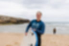Kerry holding a surf board catching waves on a beach in Lisbon