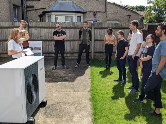 A group of people at a Heat Pump house having a tour.
