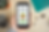Hand holding a phone displaying "Make a Donation" screen. Background has a plant, calculator, earbuds, and green cutting mat on a desk.