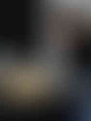 Uma jovem mulher apresenta uma cena de teatro de bonecos, ela manipula um ônibus amarelo sobre um fundo preto.