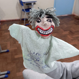 Fantoche sorridente com detalhes artesanais, em ambiente escolar.