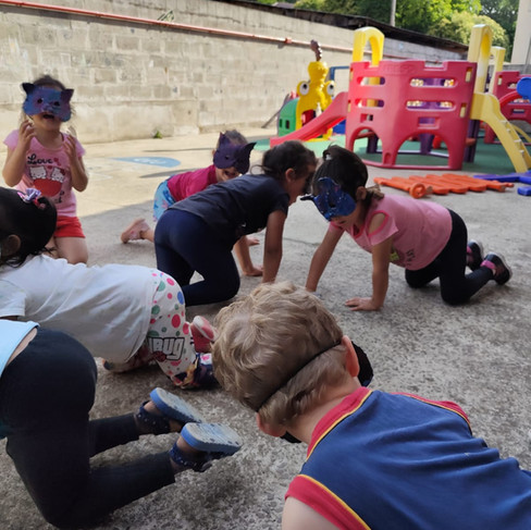 Crianças brincando com suas máscaras de papel machê no pátio da escola.