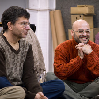 Dois homens sorrindo e conversando em um ambiente claro.