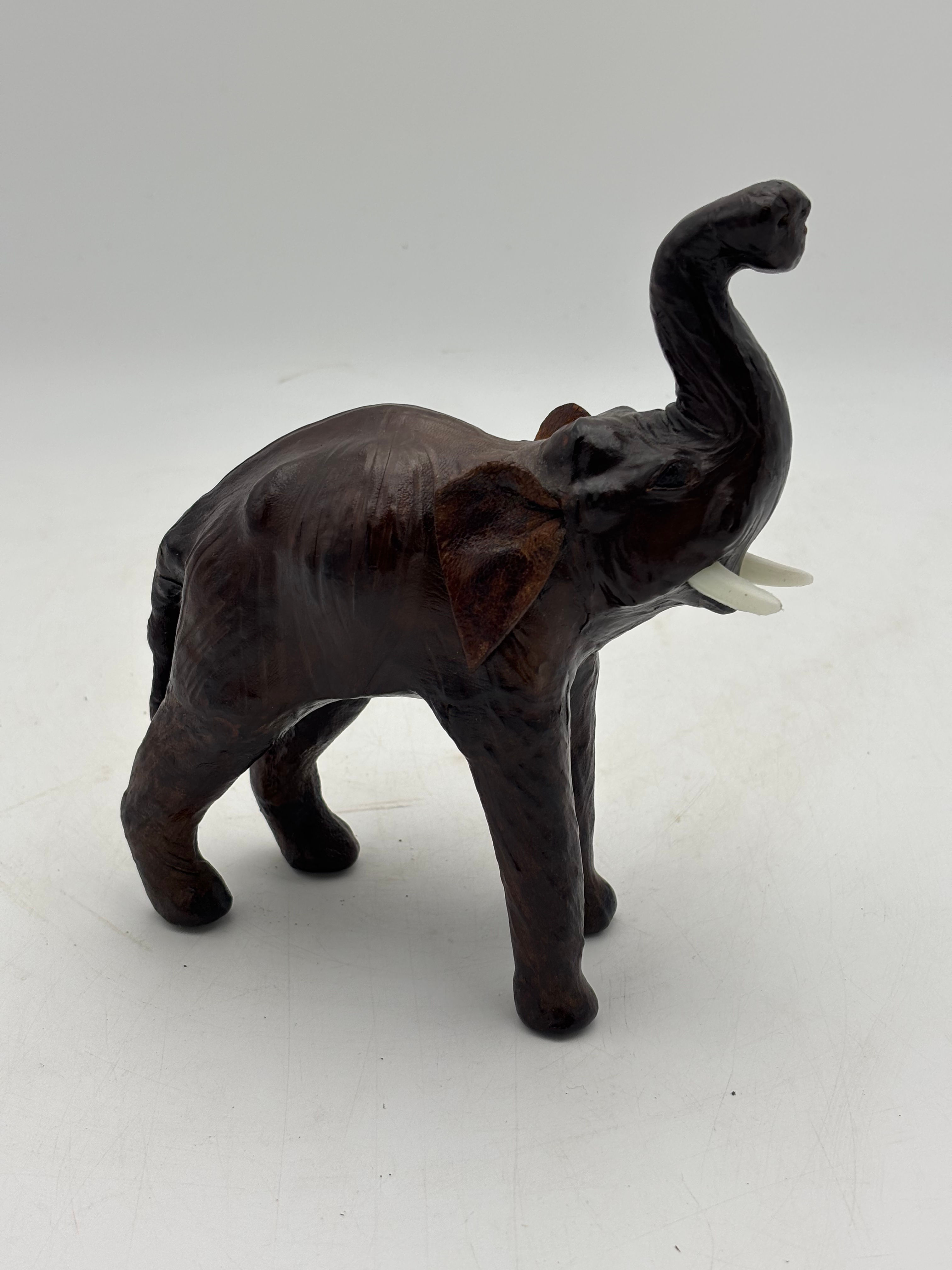 Small Vintage leather wrapped elephant figure with a raised trunk and white Plas