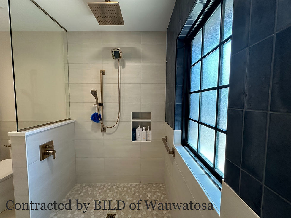 Accessible shower with neutral tile, gold fixtures, and bold blue accent tile