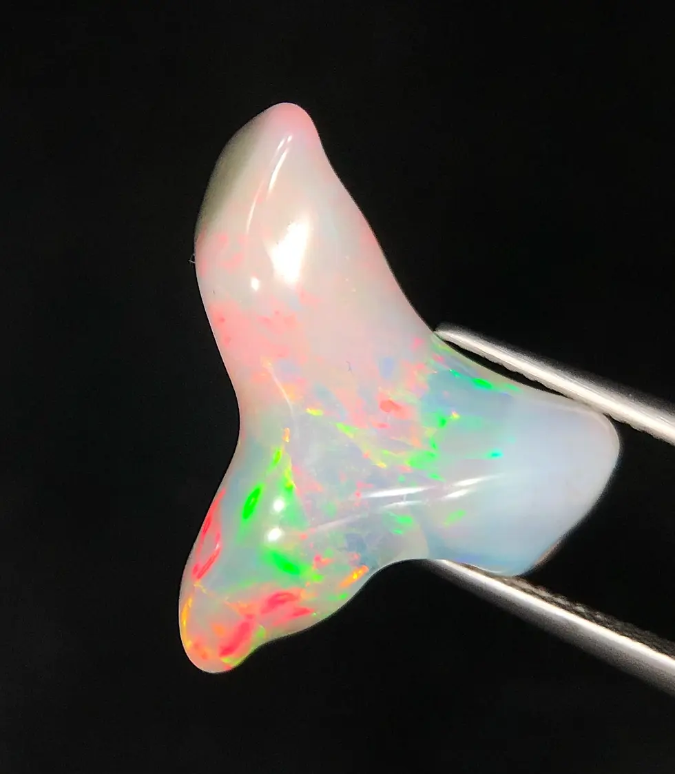 Opale éthiopienne de 9.50 carats avec reflets néon verts et rouges sur base translucide.