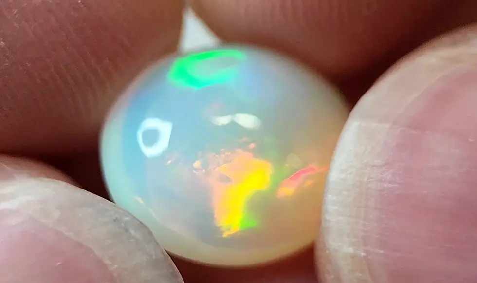 Opale Welo de 4.65 carats à dôme élevé montrant des feux jaune et vert profonds, taille ovale.