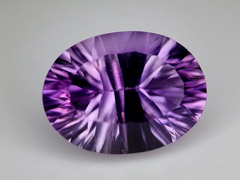 Amétrine ovale 8.13 carats, taille concave fantasy, violet profond et éclats dorés, pureté VVS.