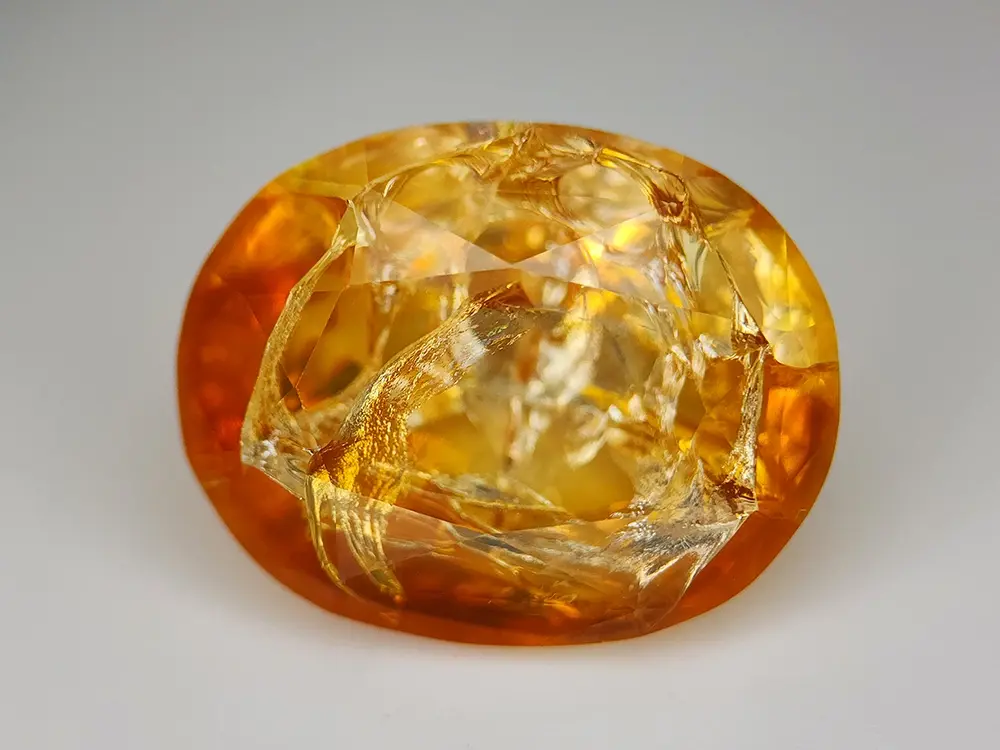 Une opale de feu orange éthiopienne de 9.58 carats, polie mais présentant de nombreuses fractures internes et de surface visi