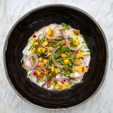 Ceviche cremoso con cebolla morada, granos de maíz y chiles.