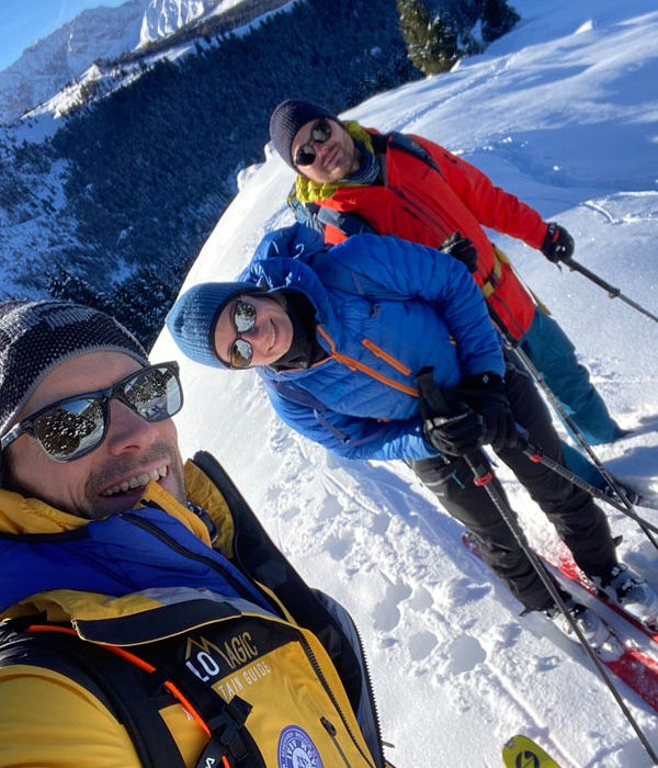 Skiers ascending the Piz Ciaulonch slopes in the Dolomites with a ski guide in Val Gardena, surrounded by snowy ridgelines and blue sky.