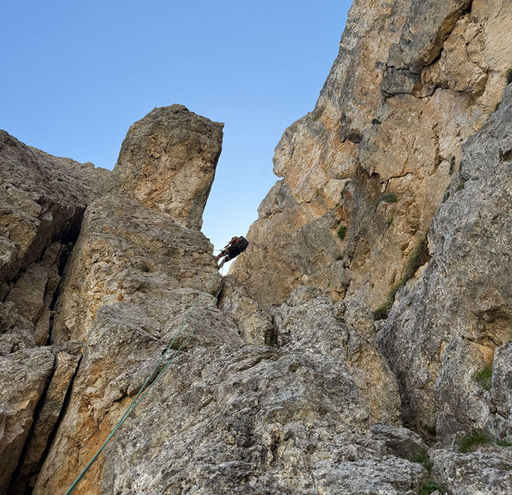 Climber ascending between Dolomite rock towers on the Fensterleturm