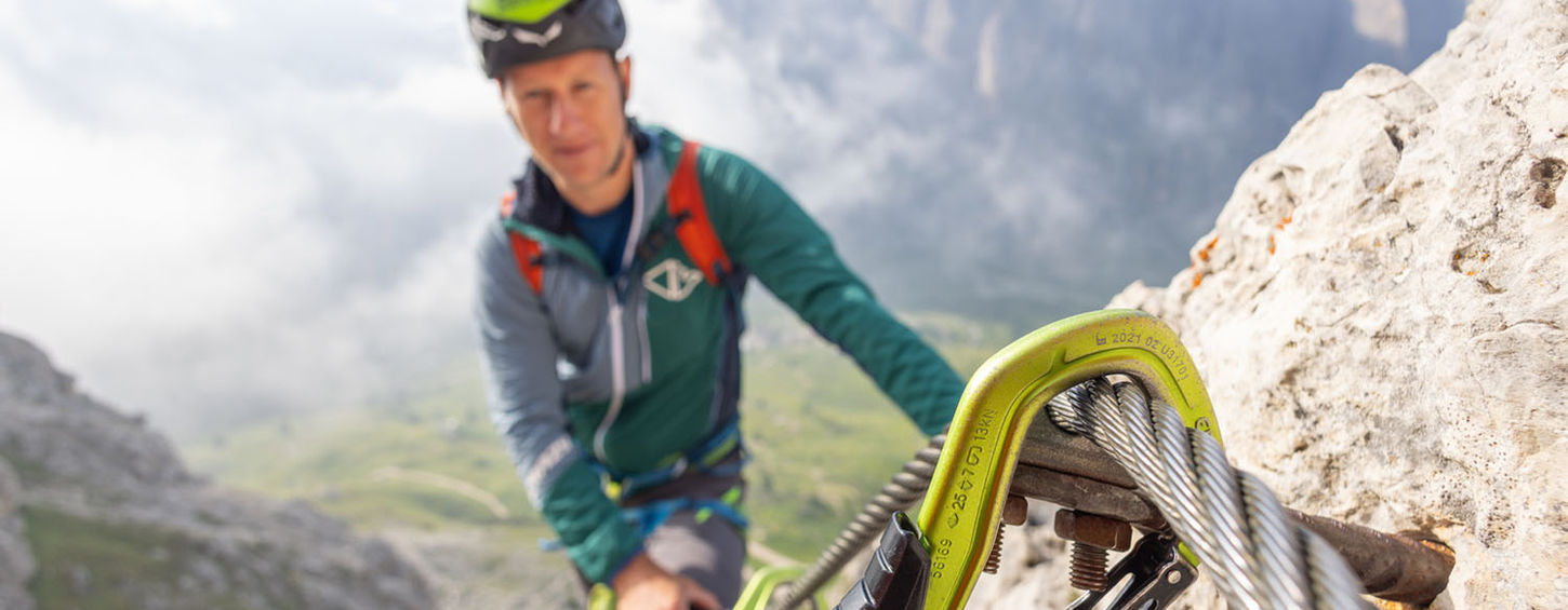 Close-up of via ferrata set clipped to steel cable during climb in the Dolomites mountains