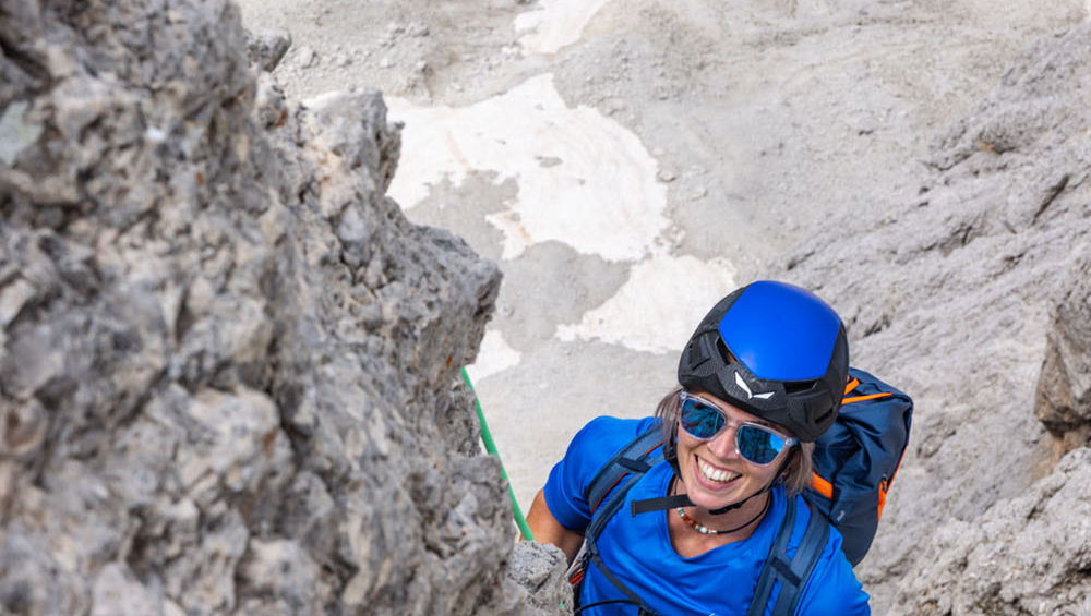 Climber ascending rock route in Sassolungo range Dolomites during guided climbing day tour
