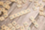 Scrabble tiles spelling HEALTH on a rustic wooden table, with scattered letters around them.