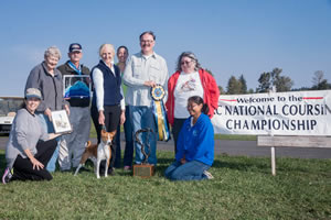 Chief poses with his tribe and American Kennel Club National Lure Coursing officials following his triumph. He is the first basenji to win the title.