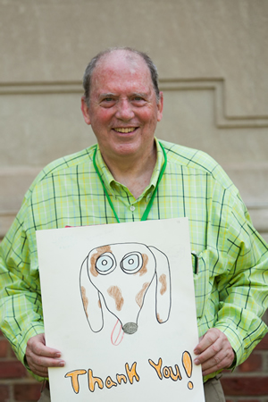 Jay Smith, Reed Intermediate School principal, holds up a thank-you poster created by students, for the therapy-dog teams. Smith showed the poster to several hundred in attendance at Newtown civic ceremony in late June.