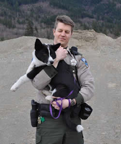 Following the pursuit and successful apprehension of a bear, Officer Nick Jorg holds his Karelian Bear Dog Colter.