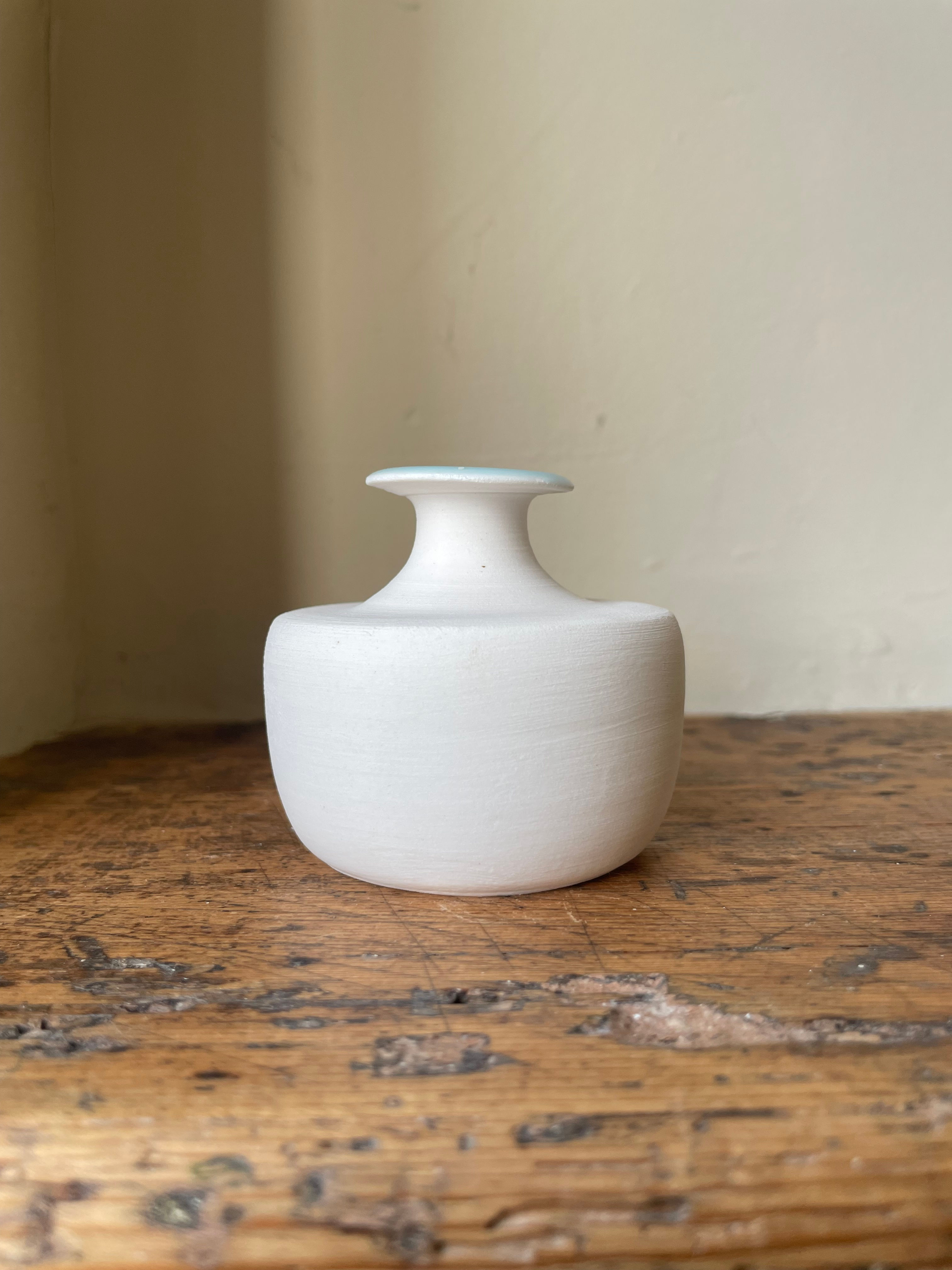 Stubby porcelain bud vase with a blue glaze flash