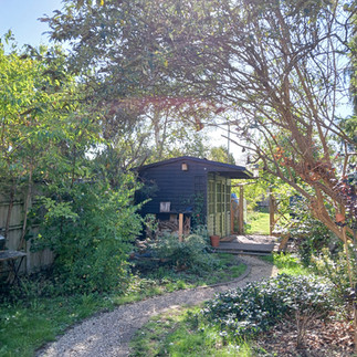 The exterior of the summerhouse has been painted black with green doors and a new gravel pathway has been laid