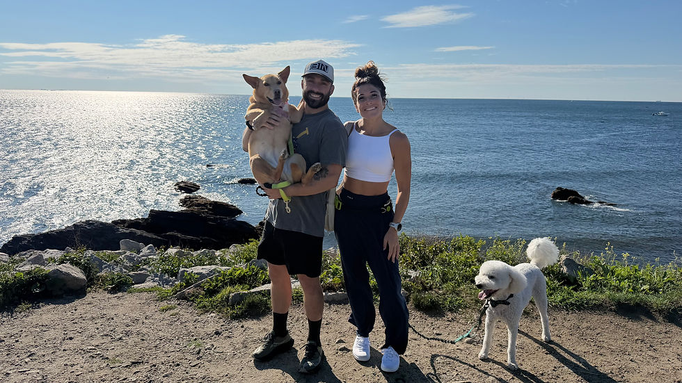 Couple holding their two dogs on the rocky coastline in Newport, Rhode Island