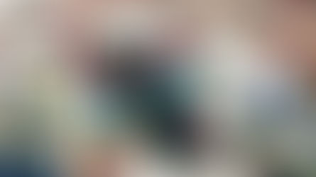 Football player in maroon jersey runs with ball, fending off opponent in white jersey. Action scene on field; teammates in background.