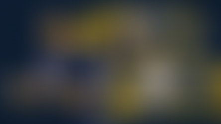 Football coach gestures with headset. Quarterbacks in Notre Dame and Texas A&M jerseys are preparing to throw. Dark, intense setting.