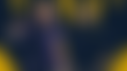 Two coaches with headsets gesture animatedly. One wears a purple shirt, the other navy with "ND" logo. Yellow and navy background.