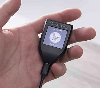 Hand holding Trezor hardware wallet - Crypto Wingman