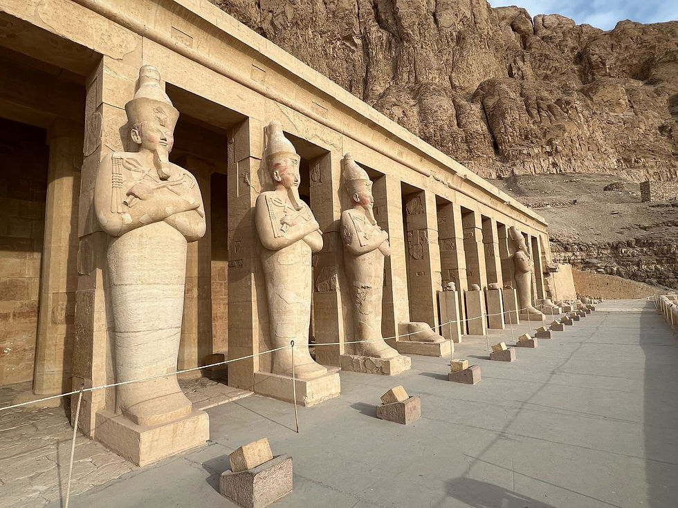 Statue's line the front of Queen Hatshepsut’s temple in the Valley of the Queens in Egypt facing the nile in the distance.