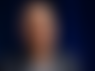 Jeff Bezos. Bald man in a suit speaks against a dark blue background, conveying a calm and confident demeanor.