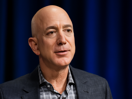 Jeff Bezos. Bald man in a suit speaks against a dark blue background, conveying a calm and confident demeanor.