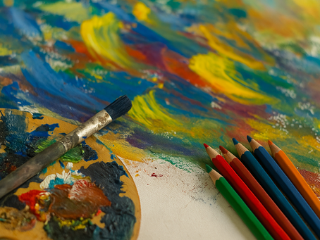 Paintbrush and colorful pencils on a vivid abstract canvas. Palette with mixed paints nearby. Creative, artistic atmosphere.