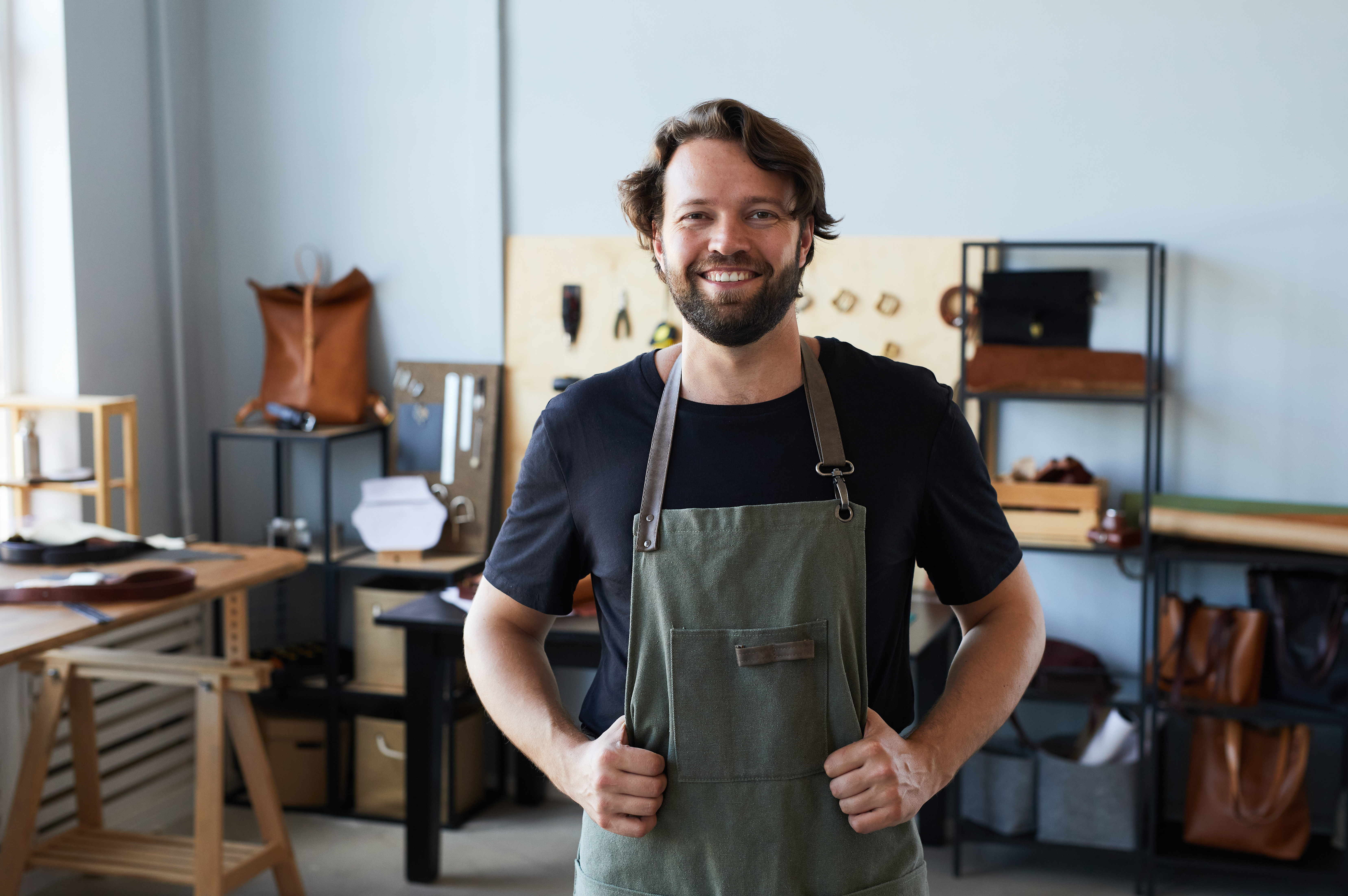 waist-up-portrait-male-artisan-wearing-apron-smiling-camera-while-posing-tanners-worksh.jp