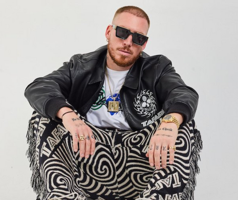A man sitting on a patterned chair wearing sunglasses and a leather jacket, representing international DJs who use EvoSounds products.