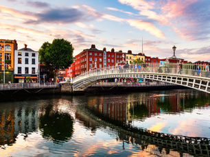 River with soft ripples and curved bridge, brightly colored buildings in the back red, yellow, blue, sunny sky with soft clouds