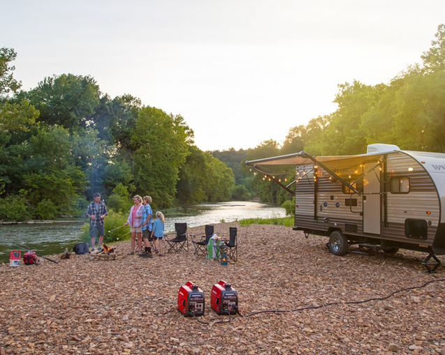Camping on the riverside with a RV trailer and two Honda EU2200 inverter generators. trees, rocks, river, rv trailer, extension cord, people, fishing poles, chairs, water, sky.