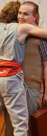 Leo receiving a hug, with a shocked look on his face. He is holding a briefcase and doesn't seem to embrace the other man.