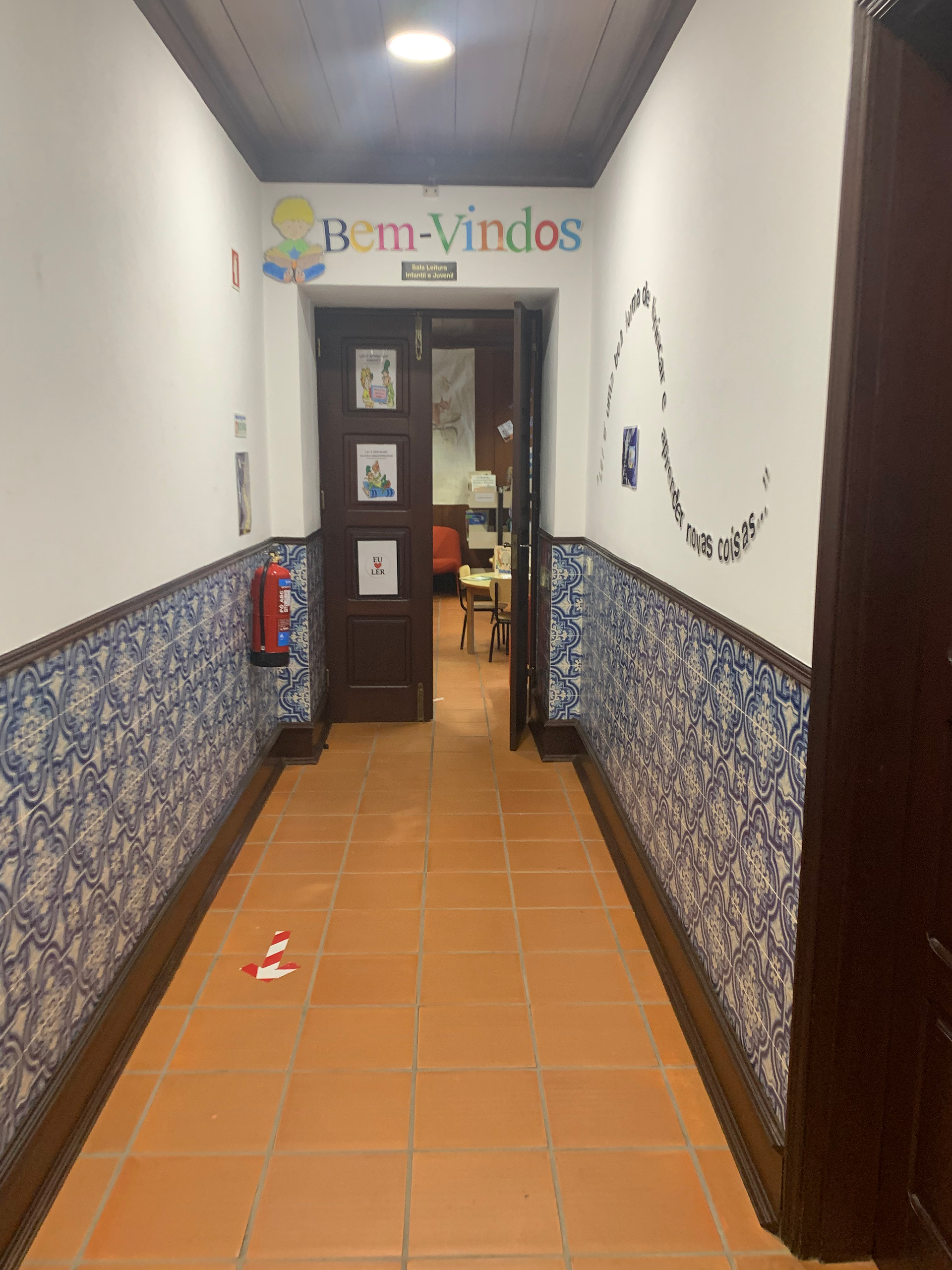 Hallway with Bem-Vindos sign, tiled walls, and door to room. Portugal Travel