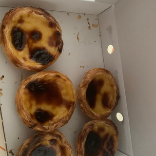 Freshly baked Portuguese custard tarts in box, delicious pastries. Portugal travel.