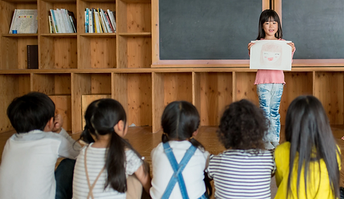 young girl reading something in front of all kids in a class of our school