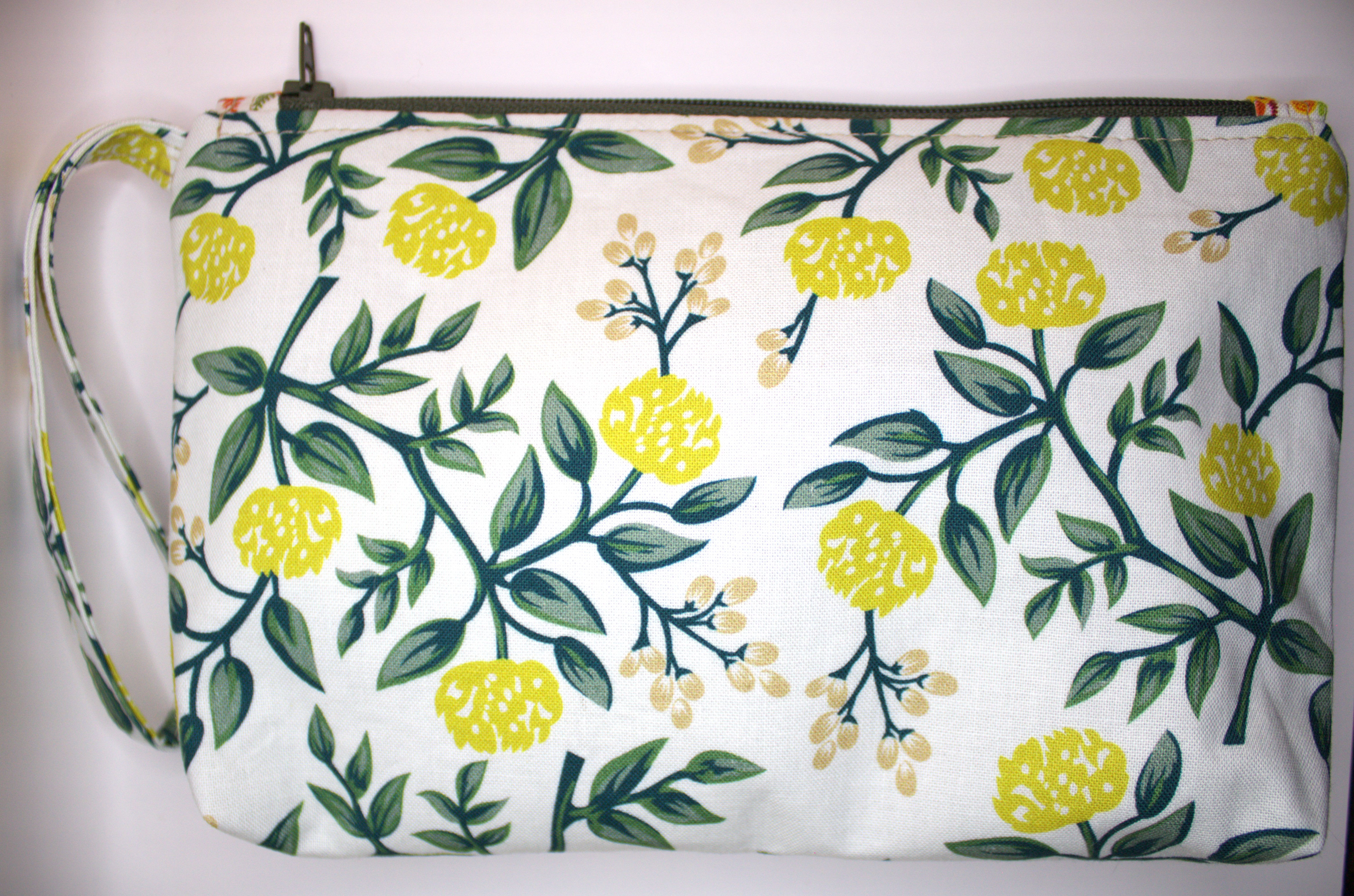 Zippered pouch approx. 8 inch wide by 6 inch. length, with wrist strap. yellow flower print fabric