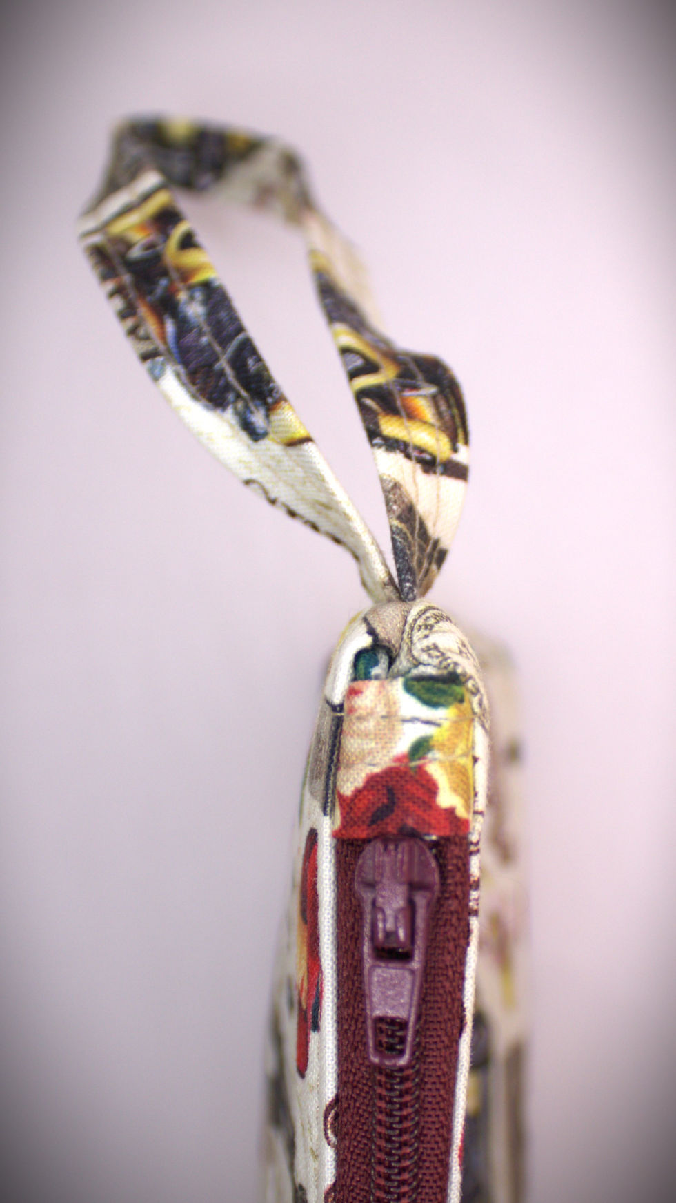 Thumbnail: Zippered pouch approx. 8 inch wide by 6 inch. length, with wrist strap. White with Icons of France collaged pattern & the words Love Paris with bunches of flowers, matching maroon colored zipper.