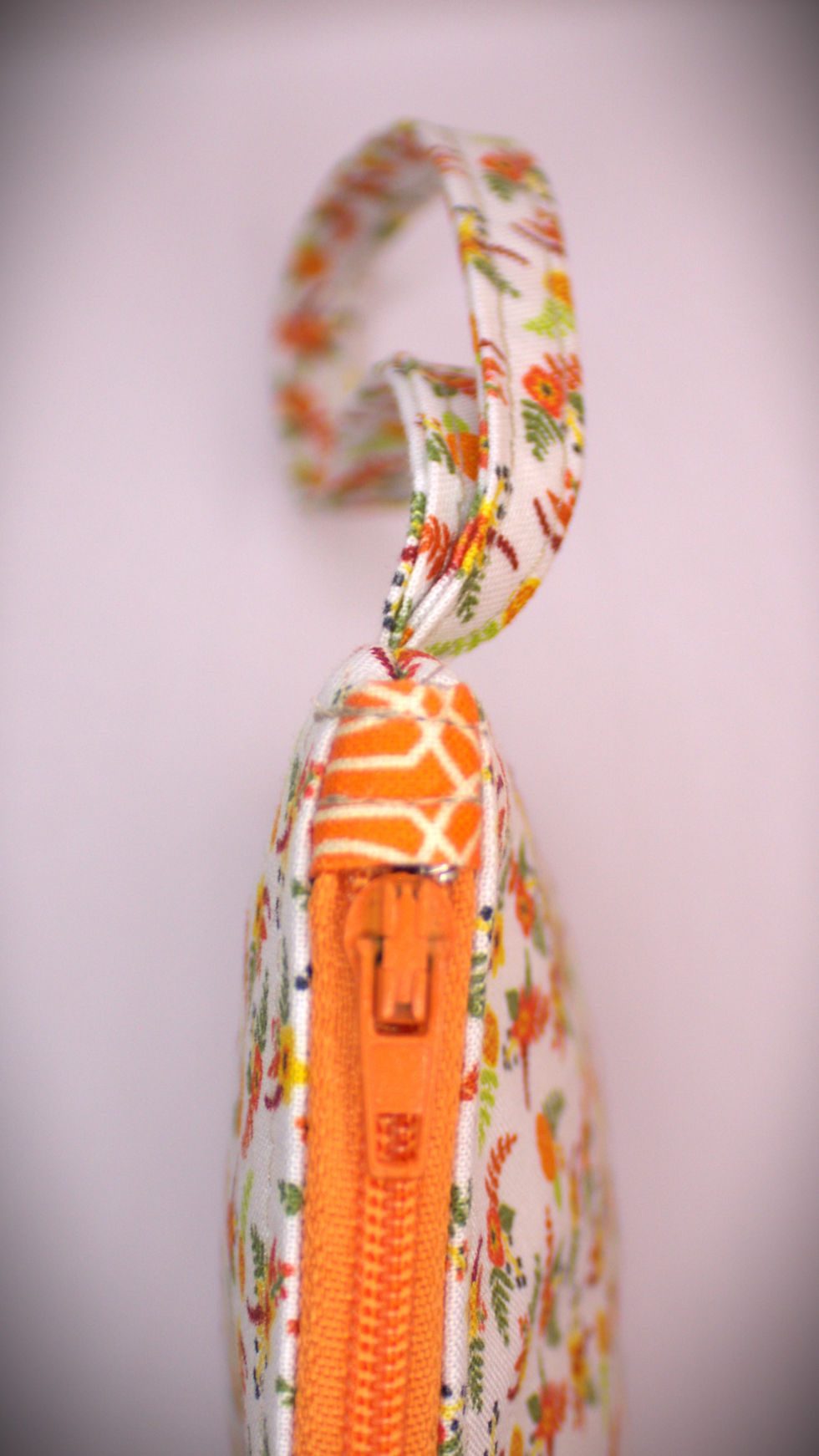 Thumbnail: Zippered pouch approx. 8 inch wide by 6 inch. length, with wrist strap. Orange & Lime floral sprigs with orange zipper.