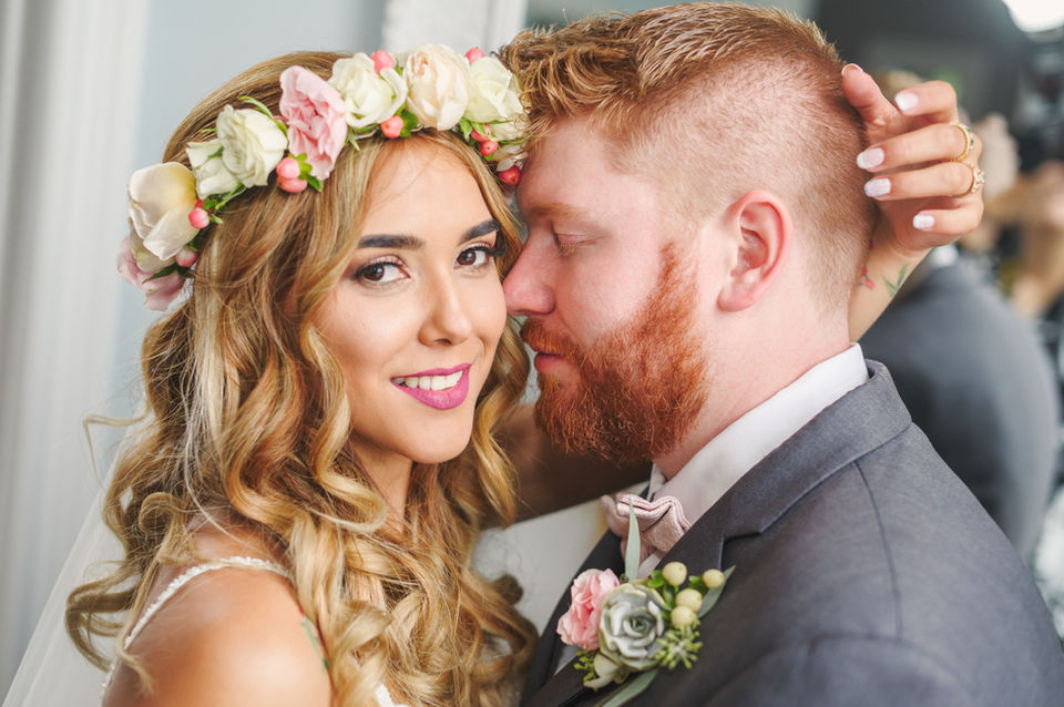 Beautiful bride looks at camera while embracing groom