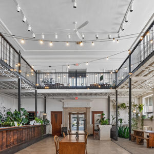 Modern interior coffee shop and wedding hall with mezzanine, string lights, plants.