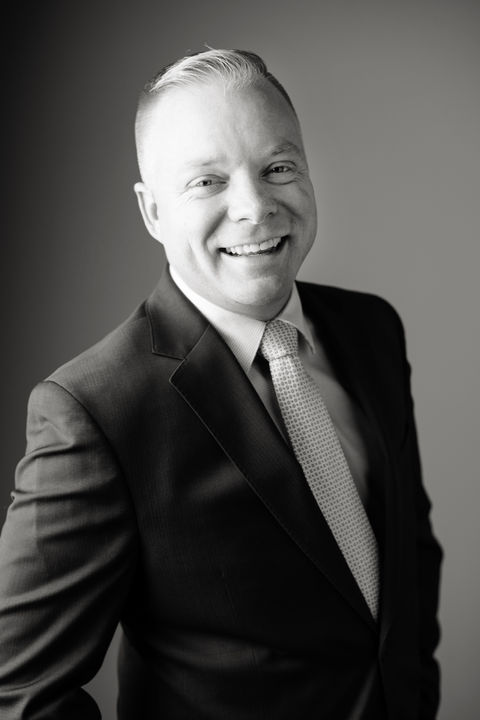 Professional headshot of a smiling man in a suit