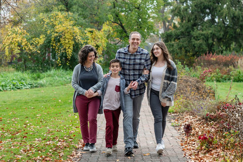 Smiling family of four walking on a park path