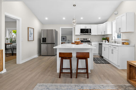 Modern kitchen with white cabinets, island, and wood stools