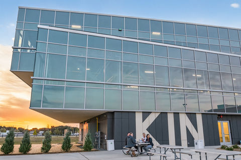 Modern glass KIN building with outdoor seating at sunset